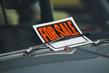 'For Sale' sign tucked under car windscreen wiper