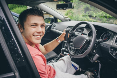 A man smiling using ability features in a car