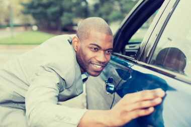 Man smiling at and caressing and his new car