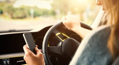 A Person Using A Mobile Phone In A Car Whilst Driving