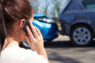 Two cars after a collision where there is a car write off and a person on the phone