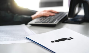 Desk with hands on a computer keyboard and car finance papers on the desk