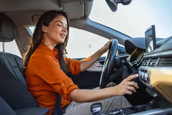 Happy business woman listening to music while traveling in her car