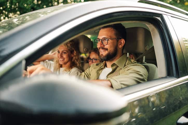 Portrait of a father smiling whilst driving his family in the family car