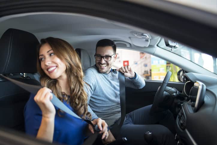 smiling couple in a car wearing seat belt