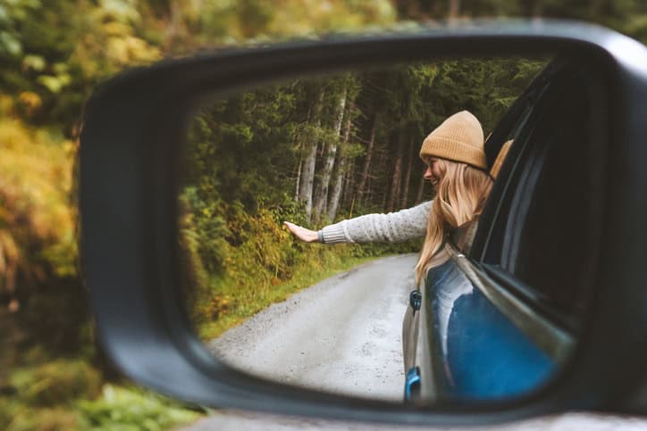 woman with hands out in a window of a car